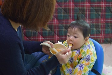 Baby and mother eating baby food, 7 months of age