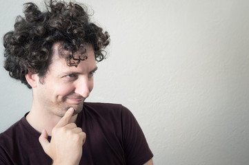 Portrait of a young, Caucasian, brunet, curly haired man with mocking expression on white background.