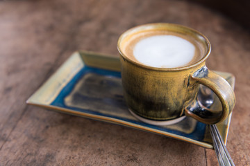 Hot coffee cappuccino cup with plate and spoon on wooden table