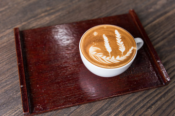 Hot coffee latte art cup with plate on wooden table