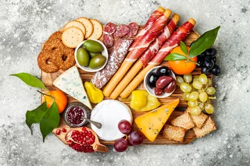 Schilderijen op glas Appetizers table with antipasti snacks. Cheese and meat variety board over grey concrete background. Top view, flat lay © sveta_zarzamora