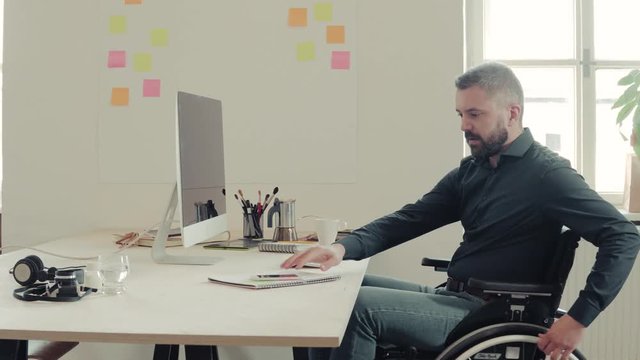 Businessman in wheelchair at the desk in his office.