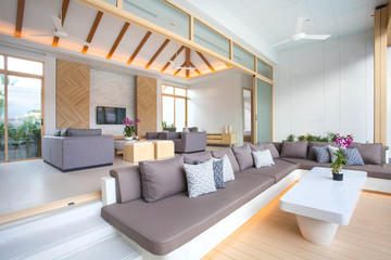 Fototapeta na wymiar Luxury interior design in living room of pool villas. Airy and bright space with high raised ceiling and wooden dining table