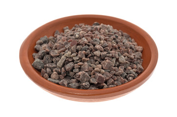 A small terracotta bowl filled with Himalayan black salt isolated on a white background.