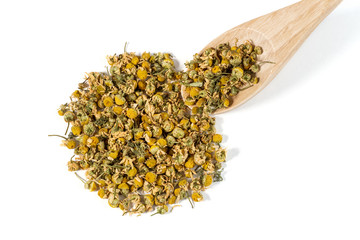 Dry Camomile Tea in a spoon on white background.