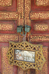 Wooden working time sign hanging on wooden door.