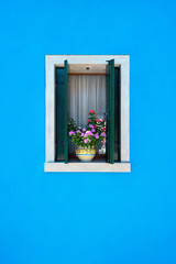 Window with green shutters and pink flowers in the pot. Italy, Venice, Burano