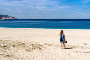 Young woman admiring Myrtos beach with white sand and blue sea water on Kefalonia island. Greece.