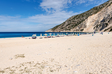 Sunbeds and parasols on beautiful Myrtos beach with white sand and blue sea water on Kefalonia island. Greece.