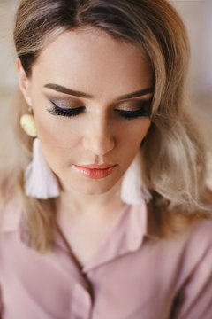 Portrait of beautiful fashionable blonde girl in a blouse with handmade and professional makeup