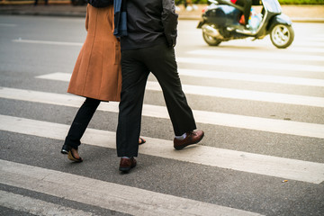 People walking across a street while motorbikes keep running on street in Hanoi, Vietnam. Closeup