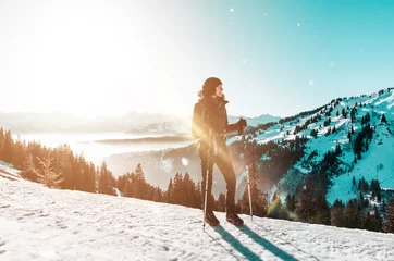 Fototapete Wintersport Woman standing with poles against winter mountains
