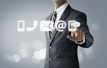 Customer service, call center service or contact us concept Businessman touching communication icons (mobile phone, telephone, mail, email address, social media) on bright tone background.