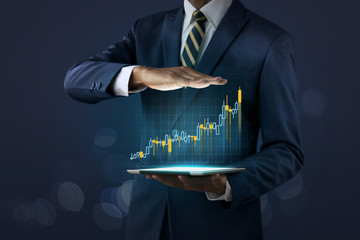 Business growth, progress or success concept. Businessman is showing a growing virtual hologram stock on dark tone background.