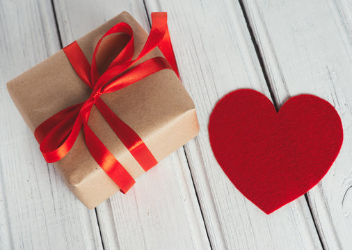 gift box tied with red ribbon and heart on wooden white table. the concept of a gift for your beloved on Valentine's day