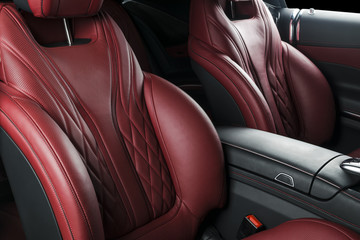 Modern Luxury car inside. Interior of prestige modern car. Comfortable leather seats. Red perforated leather cockpit with isolated Black background. Modern car interior details
