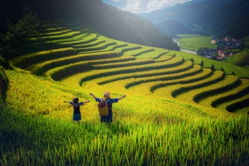 Women farmer and daughter raising arm on Rice fields terraced at sunset in Mu Cang Chai, YenBai, Vietnam.