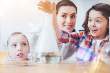 Creative chemistry. Future female scientists using a filter flask while participating in a chemical experiment held by a teacher wearing a laboratory coat at school.