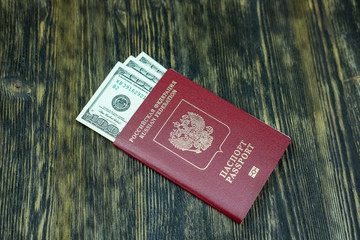 The passport of Russia with dollars lies on a wooden table.