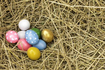 Fototapeta na wymiar multiple eggs in the straw stack. Easter eggs Pink, yellow, green, yellow, straw Easter Day.