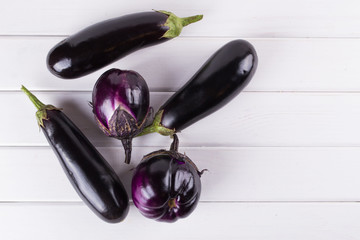 Purple eggplants of different color and variety on the white background.. Top view.