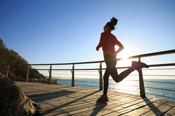sporty female jogger morning exercise on seaside boardwalk during sunrise