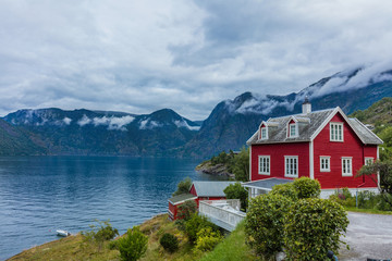Fototapeta na wymiar Wooden red cottage. Stone snowy mountains. Norway.