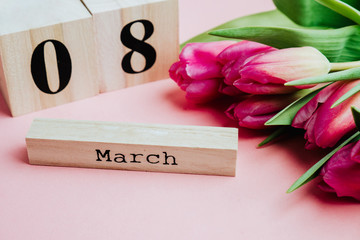 8 March Happy Women's Day concept. With wooden block calendar and pink tulips on pink background
