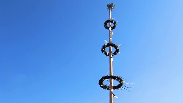 Decoration of a maypole in a small village in Lower Bavaria is rustling in the wind on a sunny day