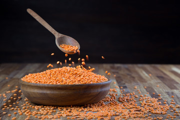 lentils red in a wooden bowl standing on the kitchen table made of oak