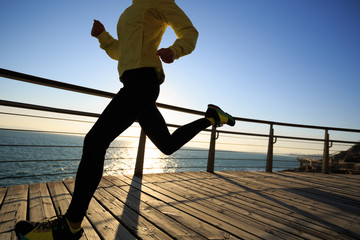 sporty female jogger morning exercise on seaside boardwalk during sunrise