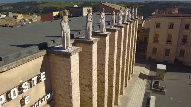 flying past sculptures atop fascist Ragusa post office