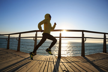 Fototapeta premium sporty female jogger morning exercise on seaside boardwalk during sunrise