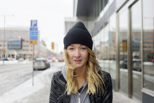 Young woman with blonde hair and knit hat in city