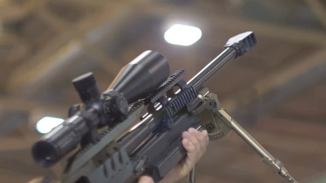 A sniper rifle in the hands of a man, an optical sight, a backdrop, a bokeh. 60 fps