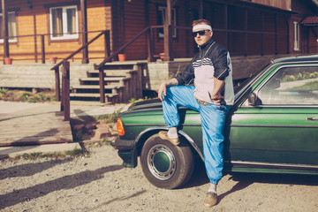 guy in the nineties stands near the car