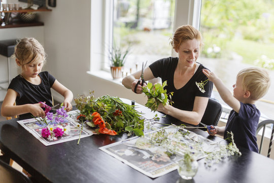 Children helping mother with arranging flower bouquet in kitchen