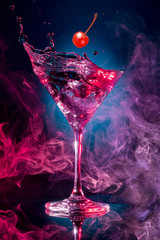 cherry falling into a cosmopolitan spashing on smoky background