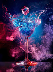 ice cube falling into splashing cocktail on smoky background