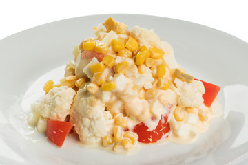 salad of cauliflower with fresh tomato and corn, with mayonnaise on a white plate