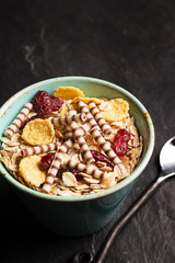 Fresh breakfast cereals with milk, raisins and corn flakes on a granite background. High angle view