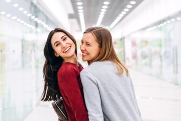 Obraz premium Two happy young girlfriends laugh and talk walking to the shops