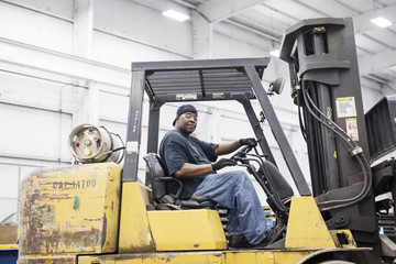 Portrait of manual worker driving forklift at metal Steel Mill