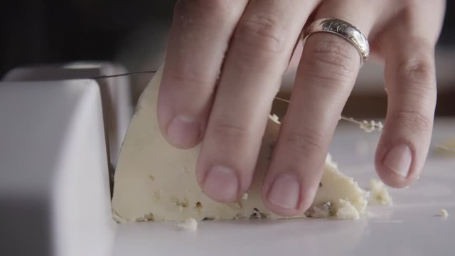 Slow motion close up, cheese cutter slices cheese