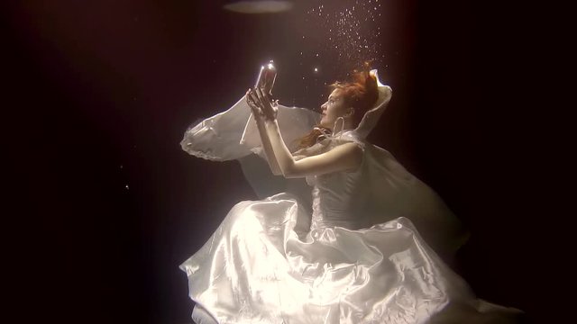 ghost of bride is wearing white dress and mantle is floating in dark water of river, holding red rose