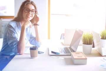 Obraz premium Young woman sitting in office table, looking at laptop computer screen . Young woman