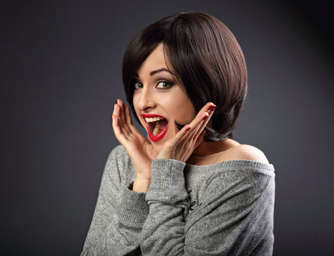 Surprising very excite woman looking with open mouth on dark grey background. Closeup portrait