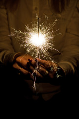 Amazing sparklers in female hands. Christmas and new year sparkler in hand toning.