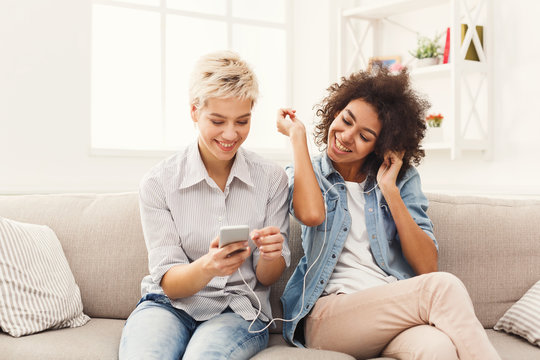 Two women listening music and sharing earphones