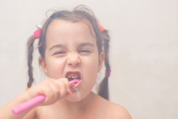 Little girl brushing her teeth isolated on white background